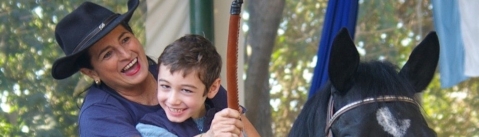 Clase de equinoterapia dirigida por Verónica Martínez con alumno montando el caballo